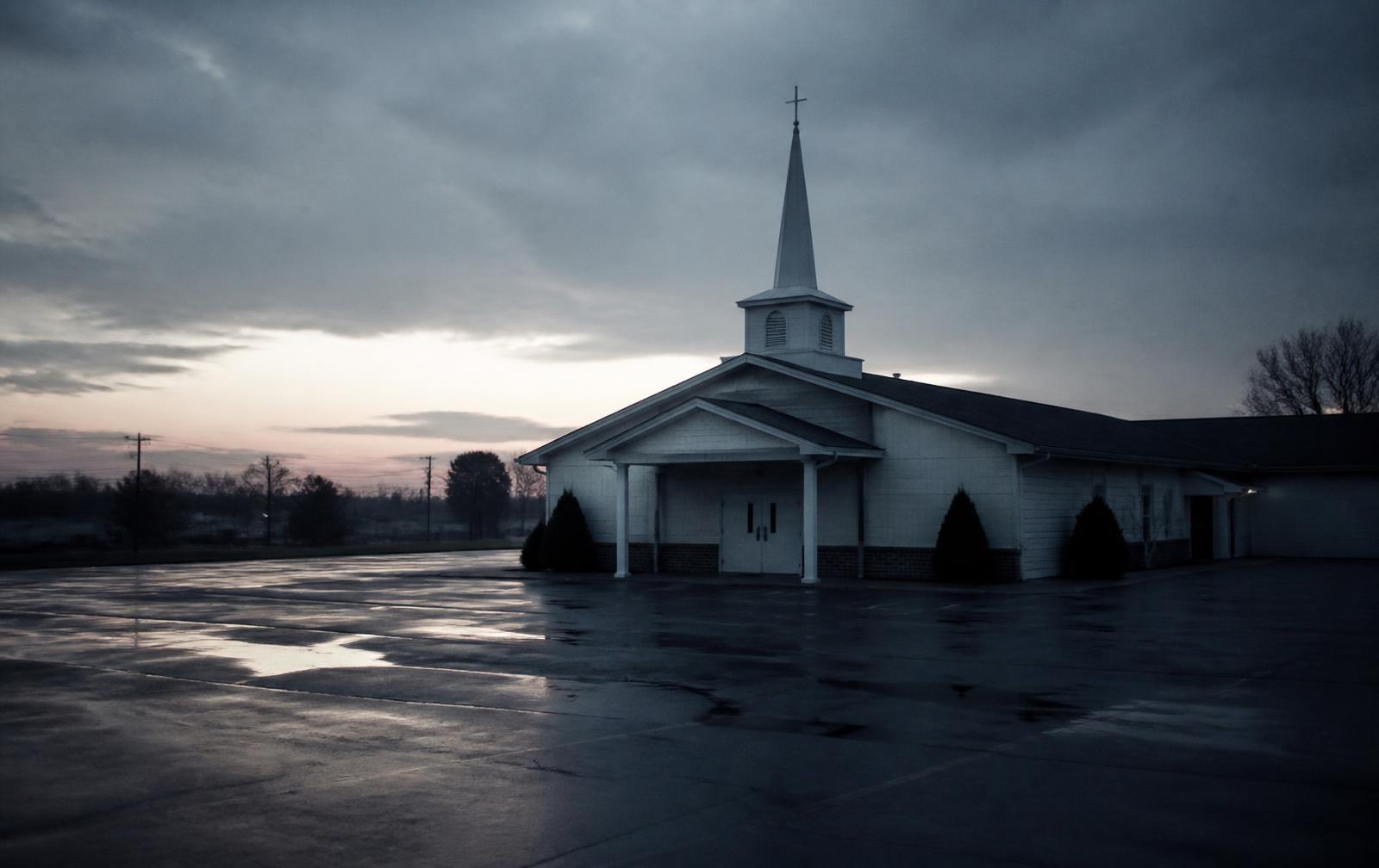 An empty church parking lot at dawn with locked doors